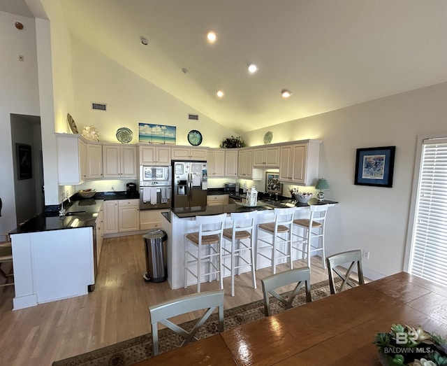 kitchen with a peninsula, light wood-style flooring, appliances with stainless steel finishes, and a breakfast bar