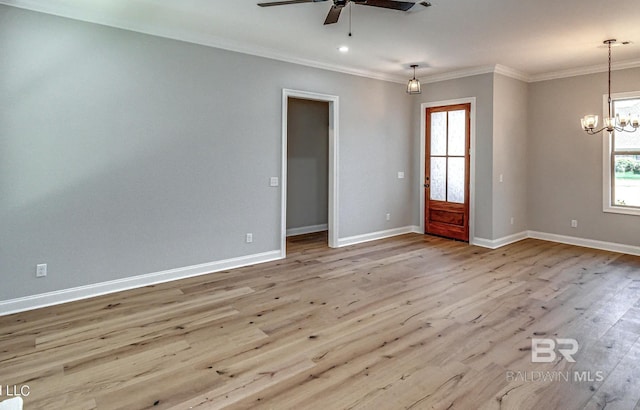 empty room featuring wood finished floors, ceiling fan with notable chandelier, baseboards, and a wealth of natural light