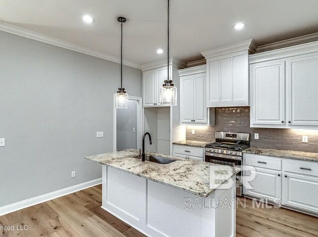 kitchen with tasteful backsplash, crown molding, white cabinets, gas stove, and a sink