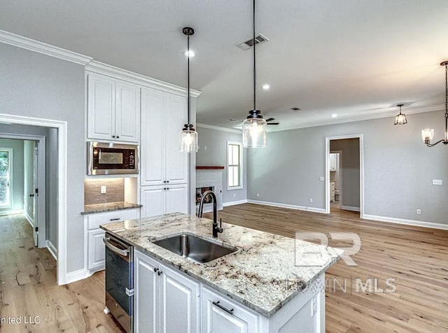 kitchen featuring built in microwave, visible vents, crown molding, and a sink