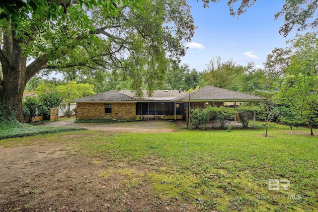 rear view of property with a lawn, brick siding, and a sunroom