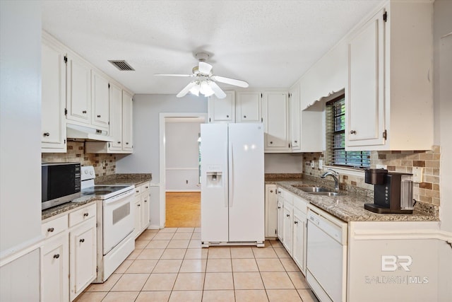 kitchen featuring visible vents, under cabinet range hood, light tile patterned flooring, white appliances, and a sink