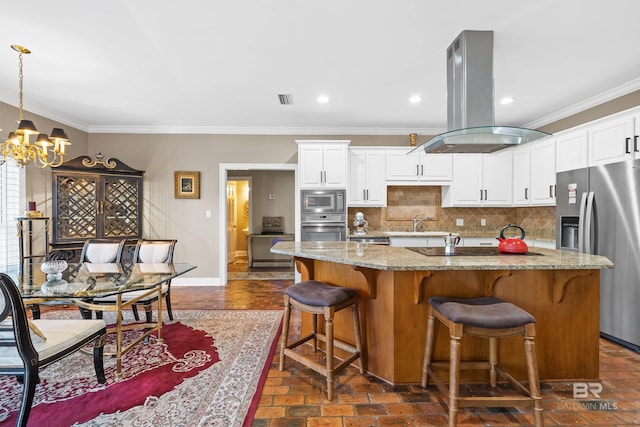 kitchen featuring baseboards, an inviting chandelier, island exhaust hood, stainless steel appliances, and tasteful backsplash