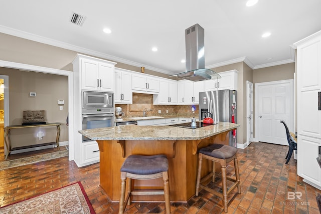 kitchen featuring visible vents, crown molding, island range hood, stainless steel appliances, and a sink