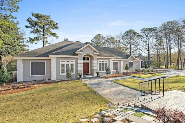 view of front of home featuring a front yard, fence, a shingled roof, a chimney, and stucco siding