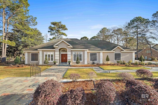 view of front of house with stucco siding, a front lawn, and fence