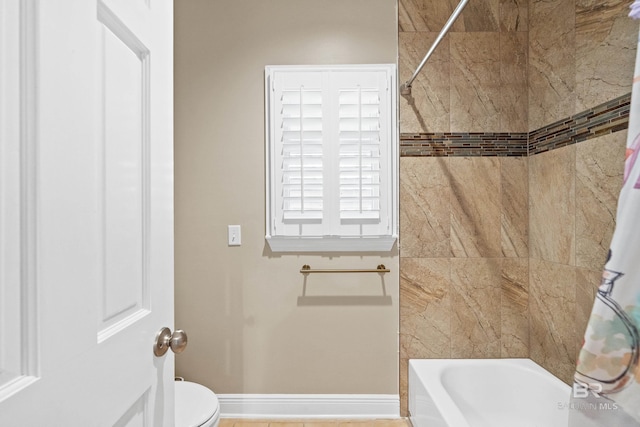 bathroom with toilet, baseboards, and shower / bath combo with shower curtain