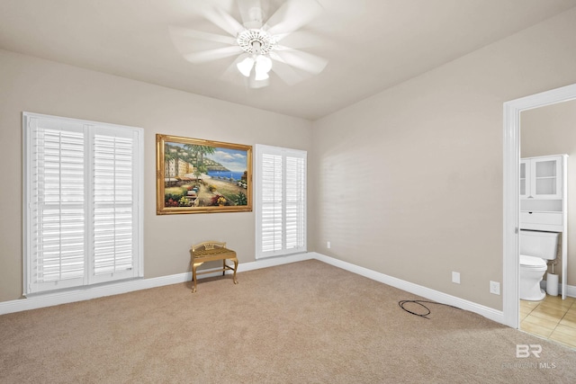 interior space with light carpet, ensuite bathroom, and baseboards