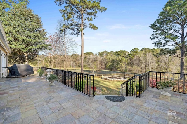 view of patio / terrace with an outdoor fire pit, a forest view, and grilling area