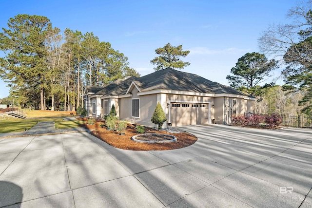 view of front of property with an attached garage, fence, driveway, and stucco siding