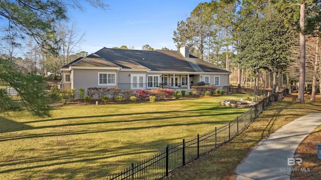 view of front of home featuring a front yard, fence, an outdoor fire pit, a chimney, and stucco siding