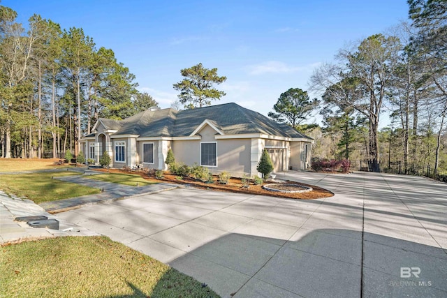 single story home with stucco siding, an attached garage, concrete driveway, and a front lawn