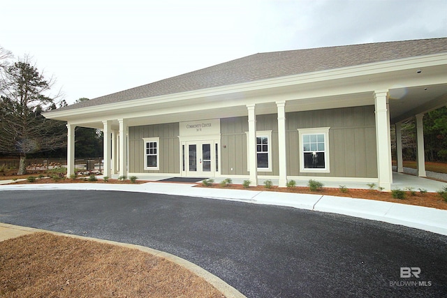 exterior space featuring french doors, roof with shingles, board and batten siding, and covered porch