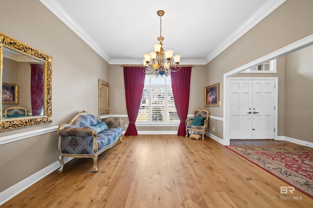 living area featuring crown molding, baseboards, wood-type flooring, and a chandelier