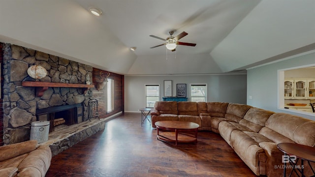 living room with a stone fireplace, ceiling fan, a tray ceiling, dark wood-type flooring, and crown molding