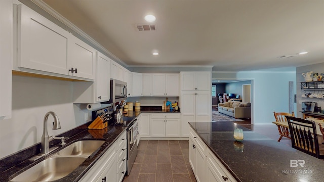 kitchen with stainless steel appliances, dark stone countertops, white cabinets, and sink