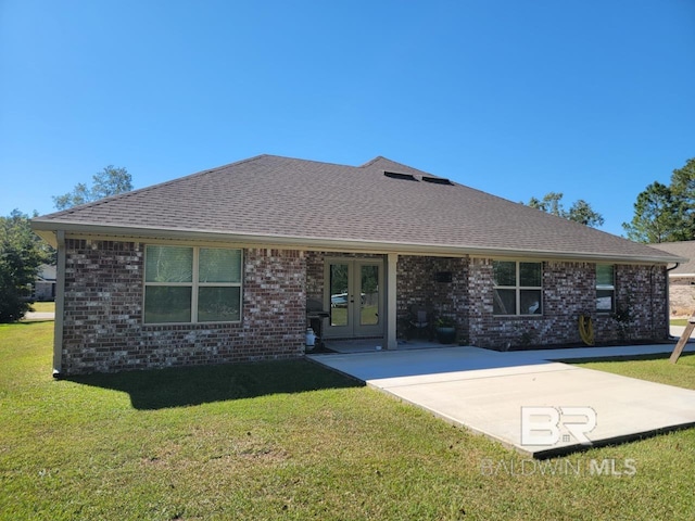 back of property with brick siding, roof with shingles, french doors, and a lawn