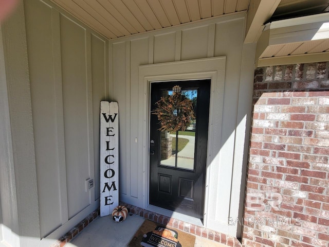 view of exterior entry featuring board and batten siding and brick siding
