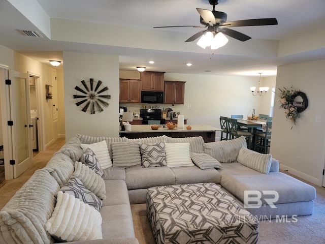 living area featuring visible vents, baseboards, ceiling fan with notable chandelier, and light carpet