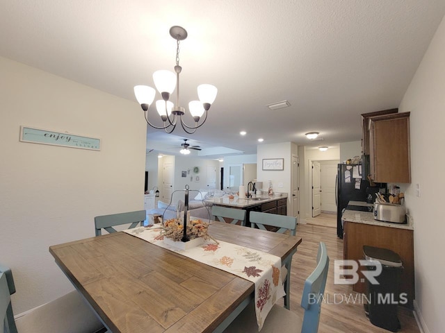 dining space featuring ceiling fan with notable chandelier and light wood-style floors