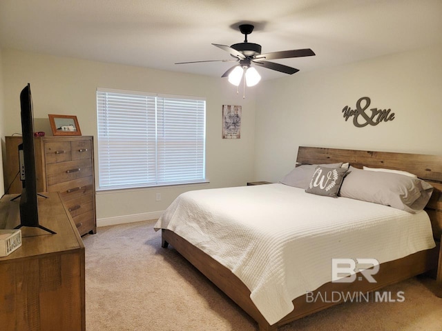 bedroom with ceiling fan, light carpet, and baseboards