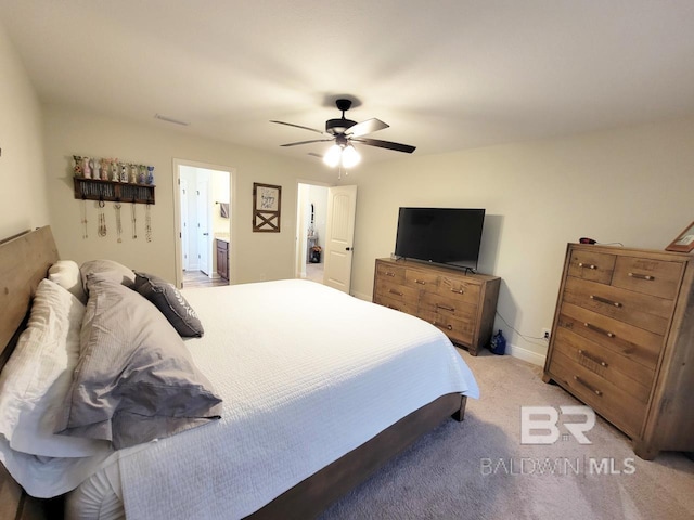 bedroom featuring a ceiling fan, ensuite bathroom, and light colored carpet