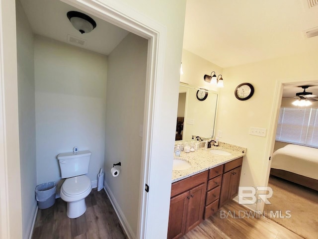 ensuite bathroom featuring toilet, ensuite bathroom, a sink, double vanity, and wood finished floors