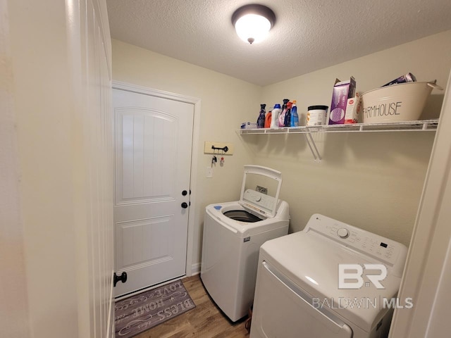 laundry area with washing machine and dryer, laundry area, light wood-style flooring, and a textured ceiling