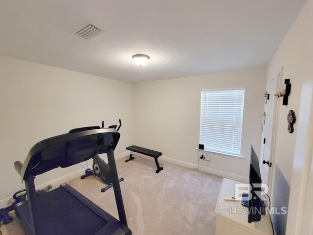 exercise room featuring a textured ceiling, visible vents, baseboards, and light carpet