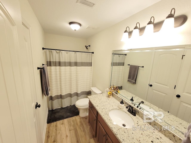 bathroom with toilet, wood finished floors, a shower with shower curtain, visible vents, and vanity