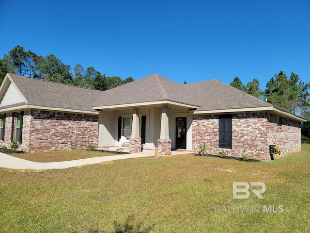 ranch-style home with a shingled roof, brick siding, and a front lawn