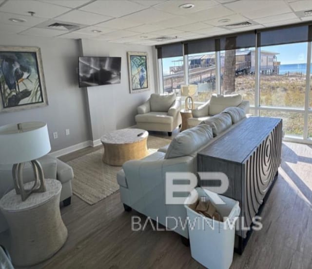 401 E Beach Blvd Unit 507, Gulf Shores, AL 36542 - living room featuring a drop ceiling, baseboards, wood finished floors, floor to ceiling windows, and plenty of natural light