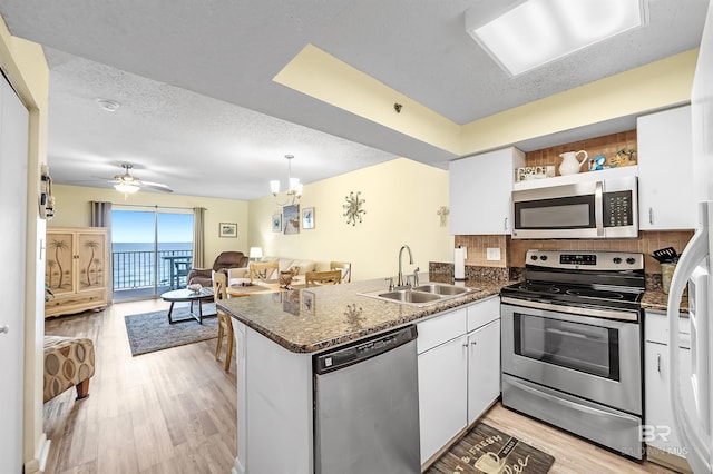 24114 Perdido Beach Blvd Unit 402, Orange Beach, AL 36561 - kitchen featuring appliances with stainless steel finishes, white cabinetry, sink, light hardwood / wood-style floors, and kitchen peninsula