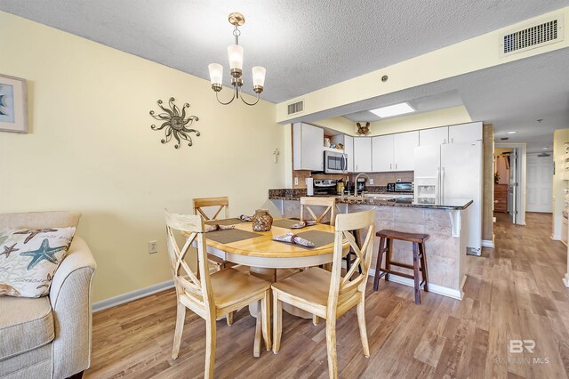 24114 Perdido Beach Blvd Unit 402, Orange Beach, AL 36561 - dining room with an inviting chandelier, sink, a textured ceiling, and light wood-type flooring