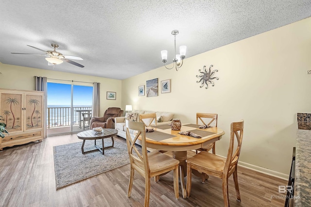 24114 Perdido Beach Blvd Unit 402, Orange Beach, AL 36561 - dining space featuring wood-type flooring, a water view, ceiling fan with notable chandelier, and a textured ceiling