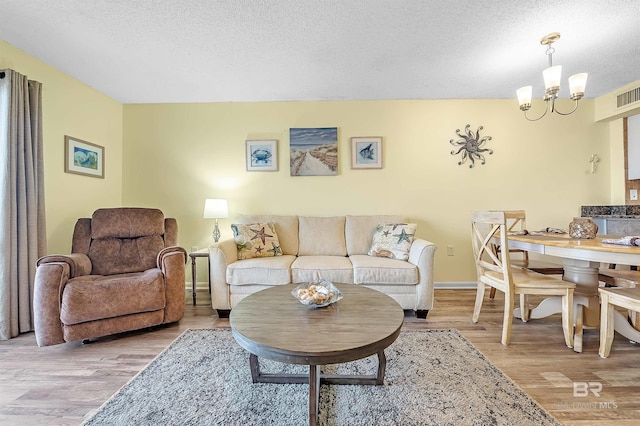 24114 Perdido Beach Blvd Unit 402, Orange Beach, AL 36561 - living room featuring an inviting chandelier, light hardwood / wood-style floors, and a textured ceiling