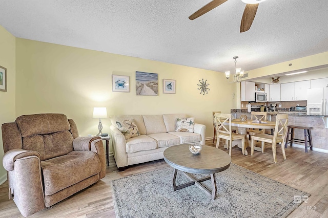 24114 Perdido Beach Blvd Unit 402, Orange Beach, AL 36561 - living room with ceiling fan with notable chandelier, light hardwood / wood-style floors, and a textured ceiling