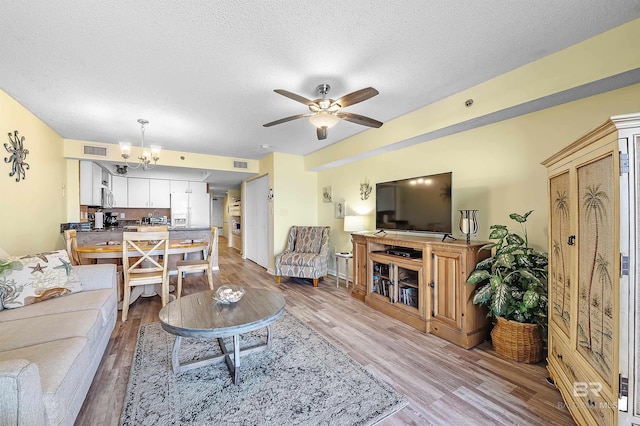 24114 Perdido Beach Blvd Unit 402, Orange Beach, AL 36561 - living room with ceiling fan with notable chandelier, a textured ceiling, and light wood-type flooring