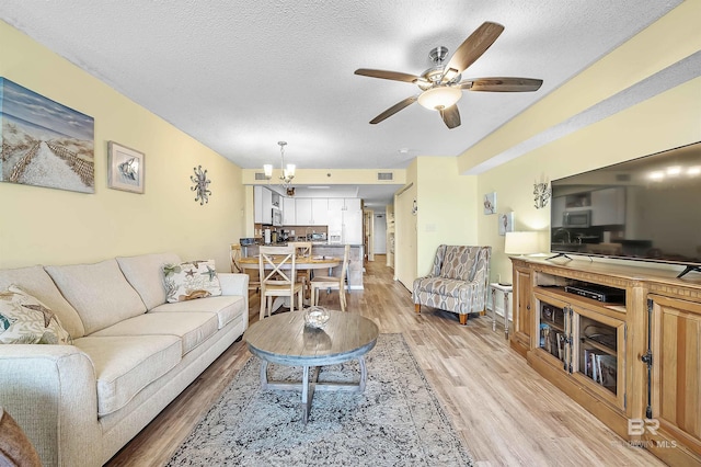 24114 Perdido Beach Blvd Unit 402, Orange Beach, AL 36561 - living room with ceiling fan with notable chandelier, light hardwood / wood-style flooring, and a textured ceiling