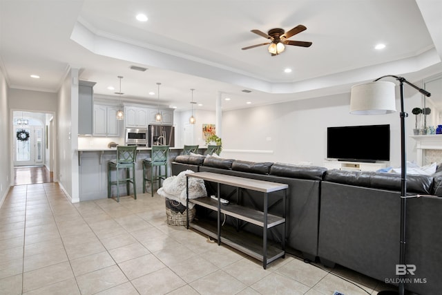 tiled living room featuring ceiling fan, crown molding, and a tray ceiling