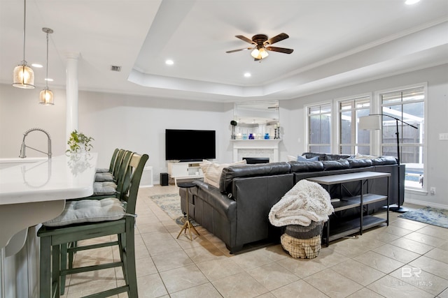 tiled living room featuring ceiling fan, crown molding, a raised ceiling, and sink