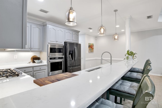 kitchen featuring kitchen peninsula, stainless steel appliances, a kitchen breakfast bar, and hanging light fixtures