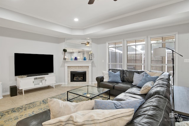 living room with ceiling fan, ornamental molding, light tile patterned floors, and a tray ceiling