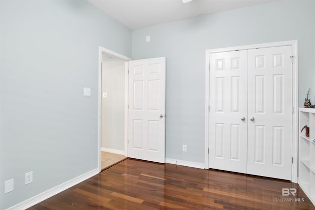 unfurnished bedroom with a closet and dark hardwood / wood-style floors