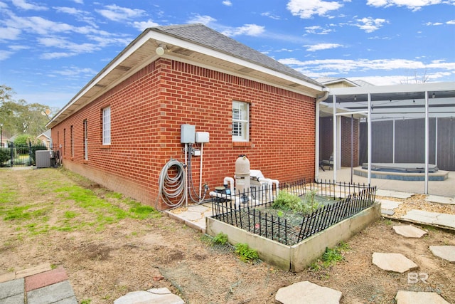 view of property exterior featuring central air condition unit and glass enclosure