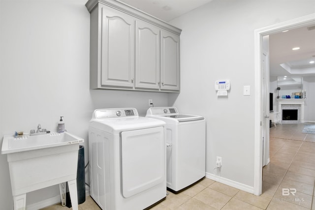 washroom with sink, washer and clothes dryer, light tile patterned flooring, and cabinets