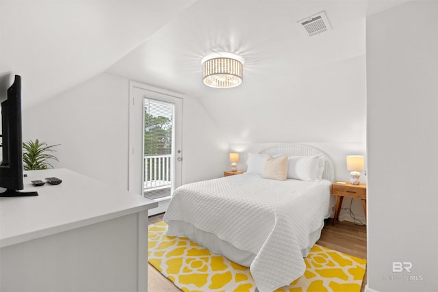 bedroom with visible vents, access to outside, light wood-style floors, and lofted ceiling
