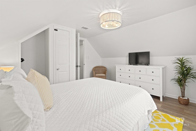 bedroom featuring visible vents, baseboards, vaulted ceiling, and wood finished floors