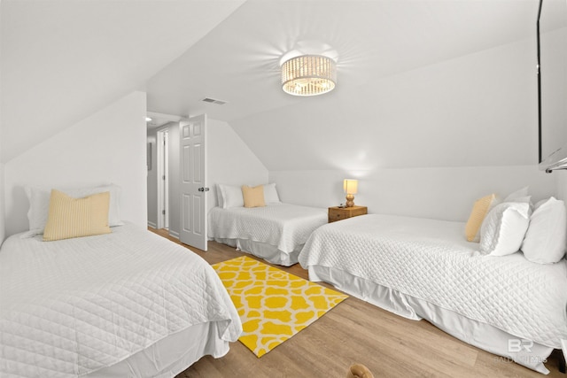 bedroom with wood finished floors, lofted ceiling, and visible vents