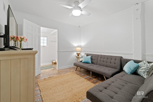 living area featuring light wood finished floors, wainscoting, and a ceiling fan